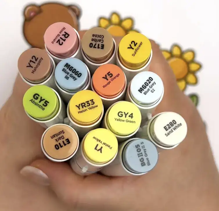 Hand met alcoholstiftdoppen die verschillende kleurtonen tonen die worden gebruikt om te mengen.