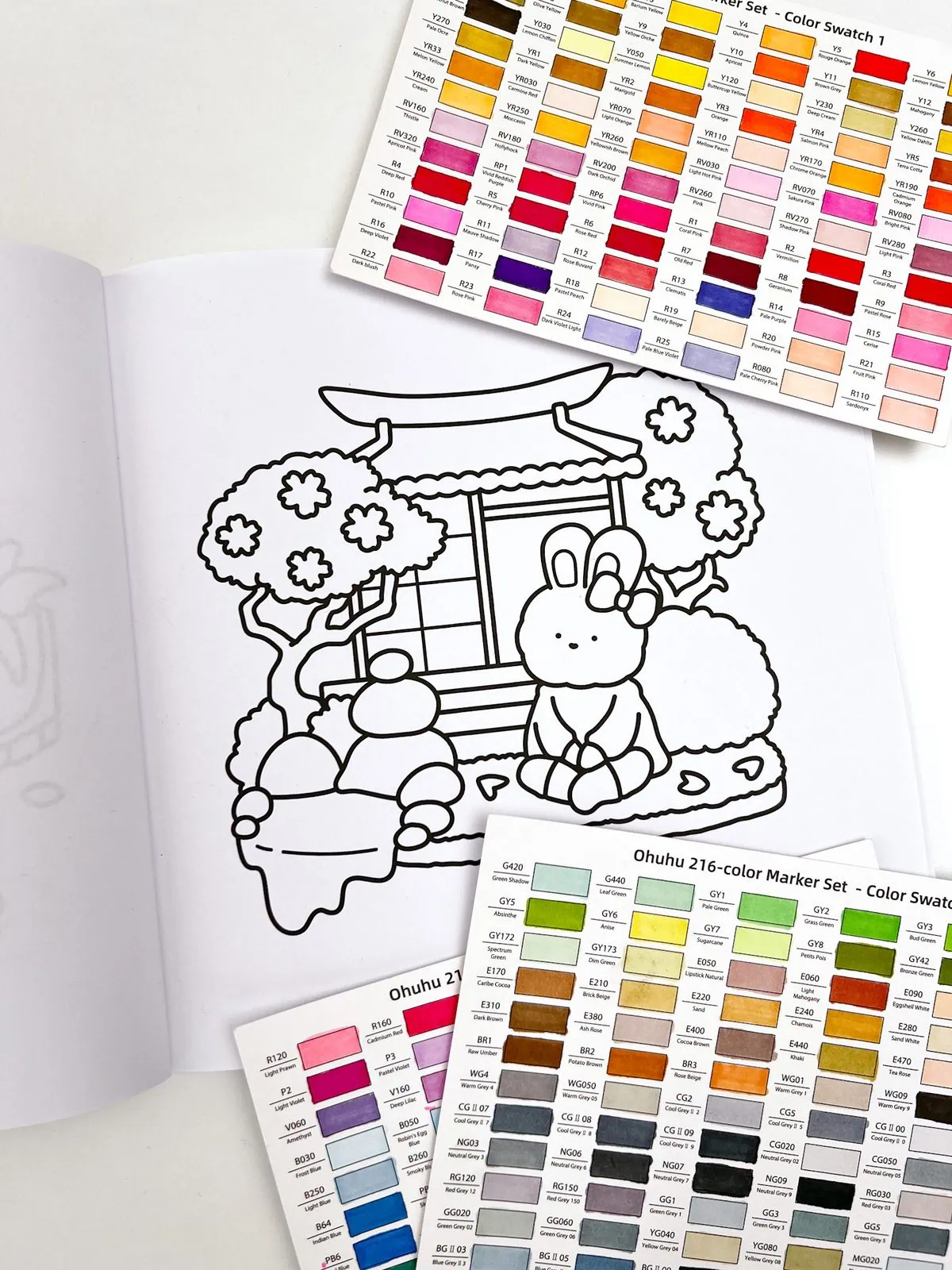 Open adult coloring book showing zen garden bunny illustration with marker swatch cards