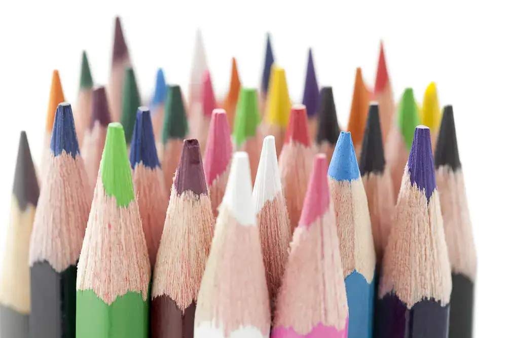 Sharpened colored pencils in assorted colors grouped together against a white background